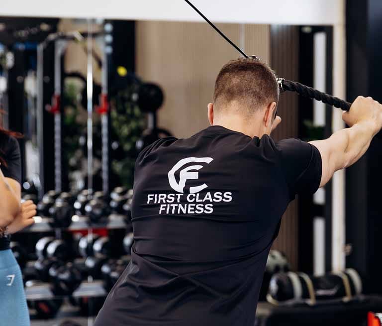 man in zwart t-shirt traint met fitness poulie